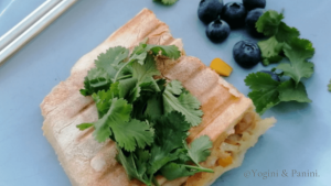 Half cut of a tuna mayo corn Panini with coriander & blueberries